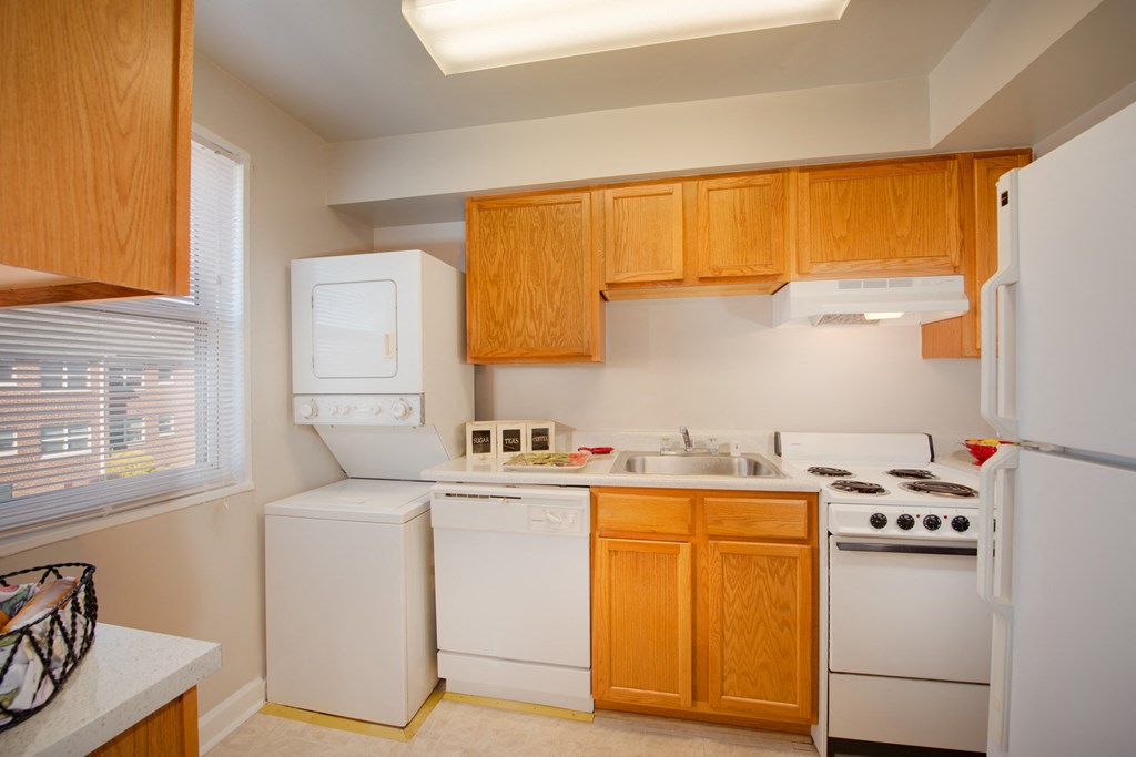 a kitchen with white appliances and wooden cabinets and a window