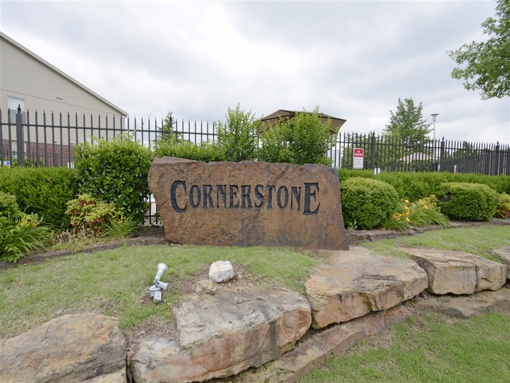 a concrete sign sitting in the grass next to some rocks