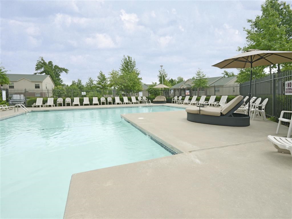 a swimming pool with chairs and umbrellas next to it
