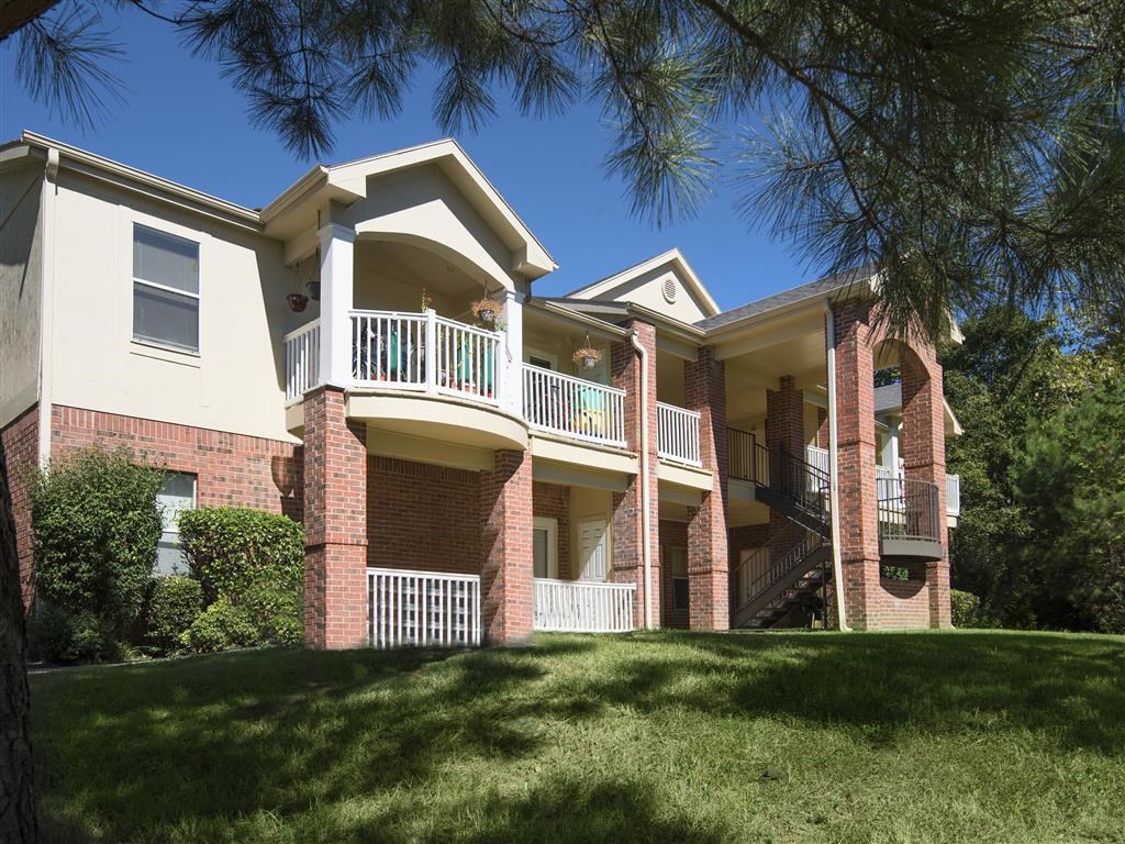 an exterior view of an apartment building with grass and trees