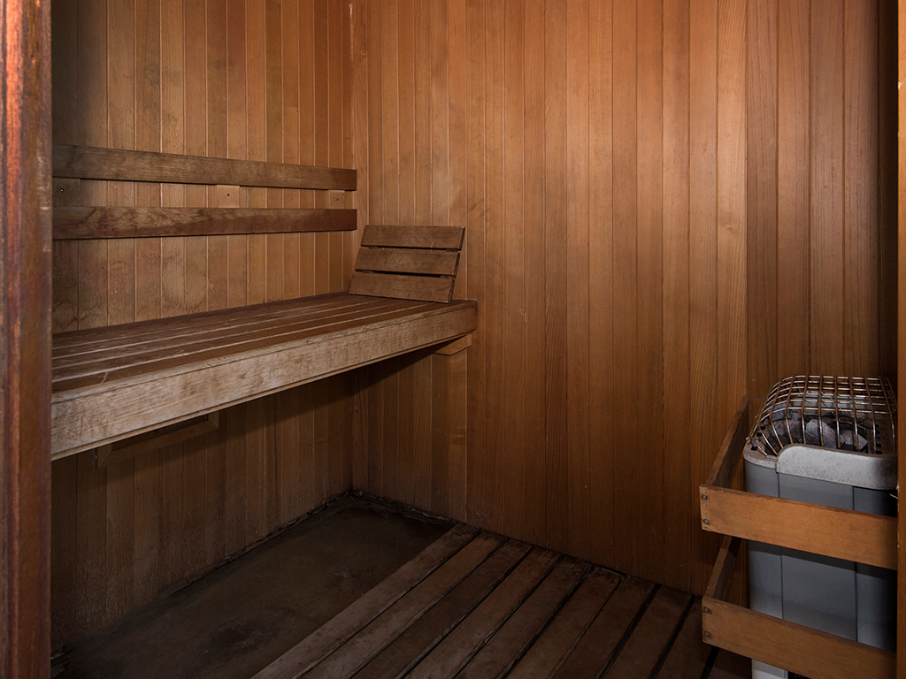 a wooden sauna with wooden benches and a trash can