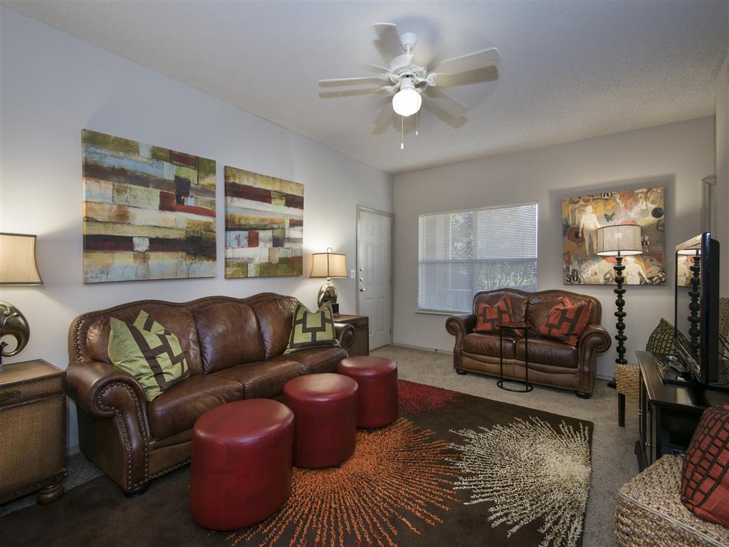 a living room with leather furniture and a ceiling fan