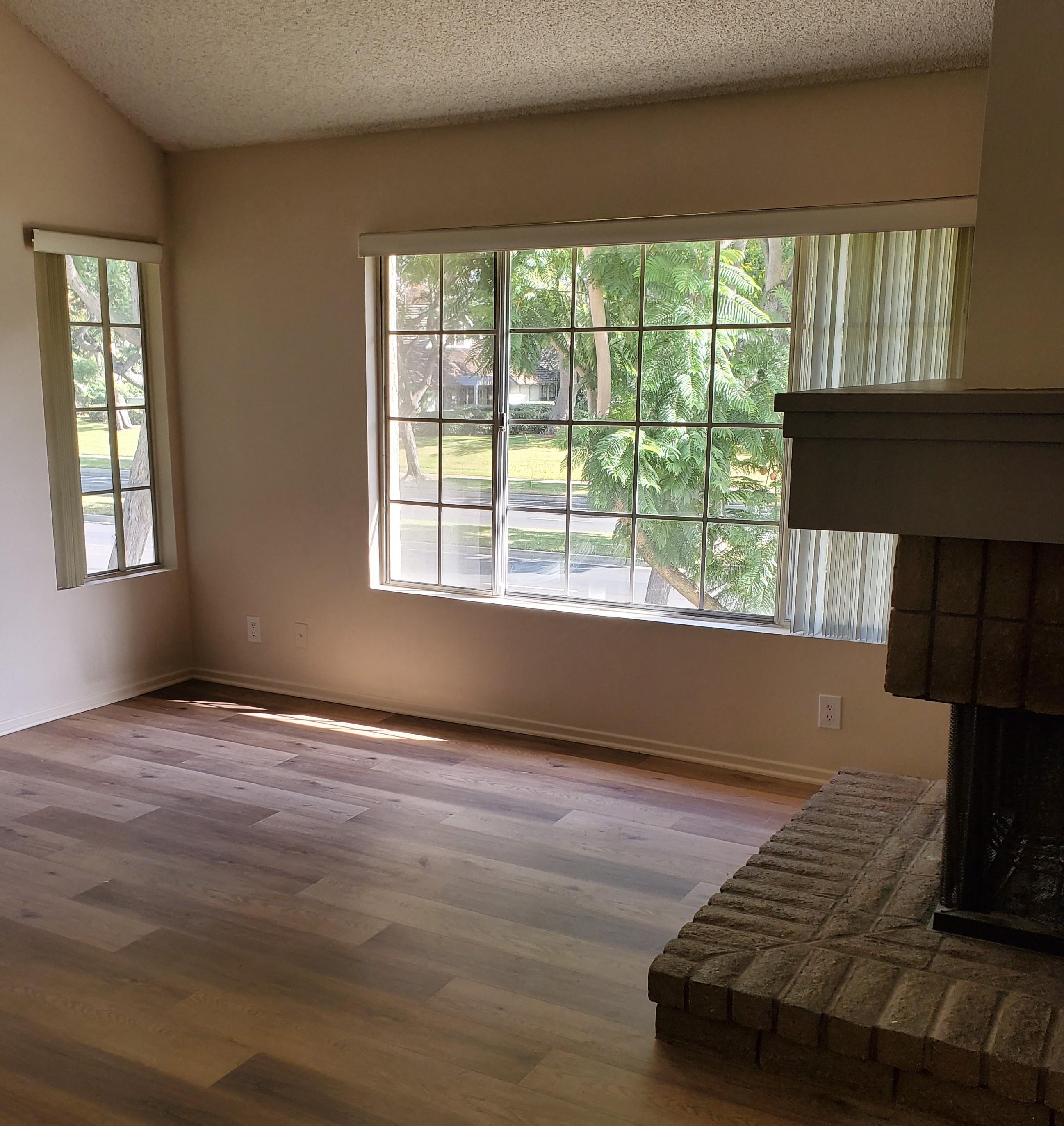 an empty living room with a fireplace and a large window