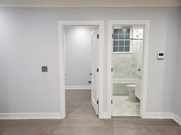 a white bathroom with a door to a toilet and a sink
