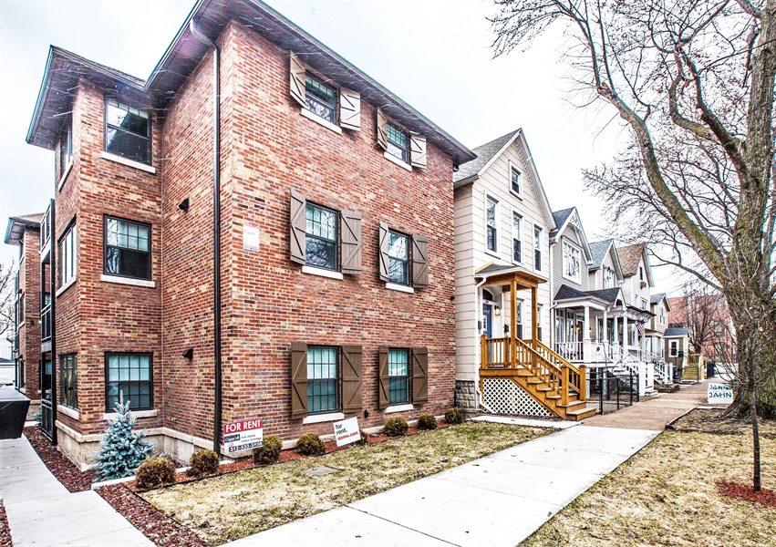 a brick house with a sidewalk in front of it
