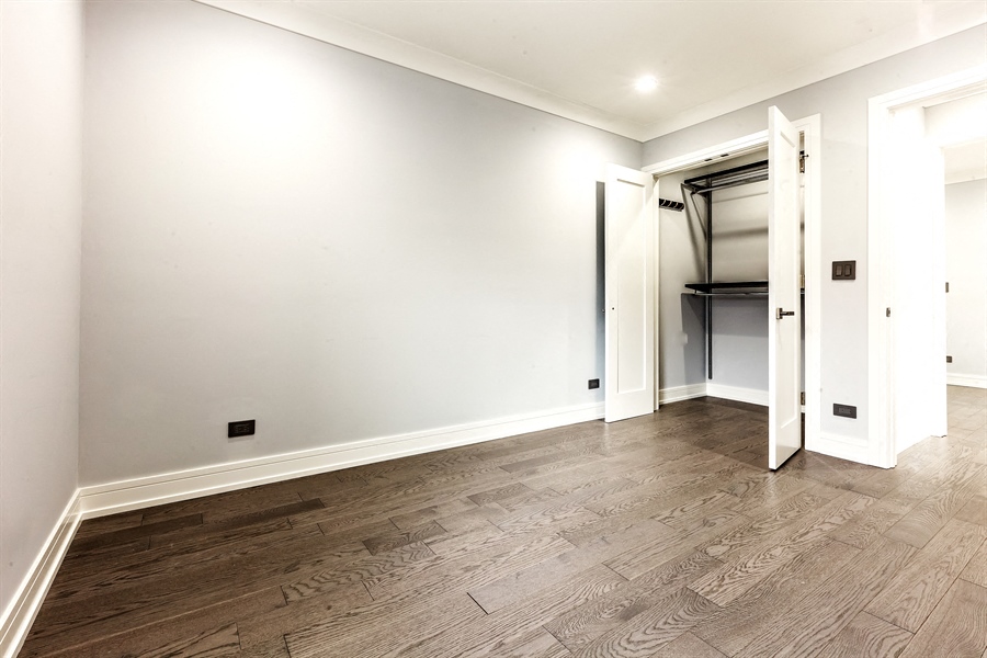 a living room with white walls and wood flooring and a closet