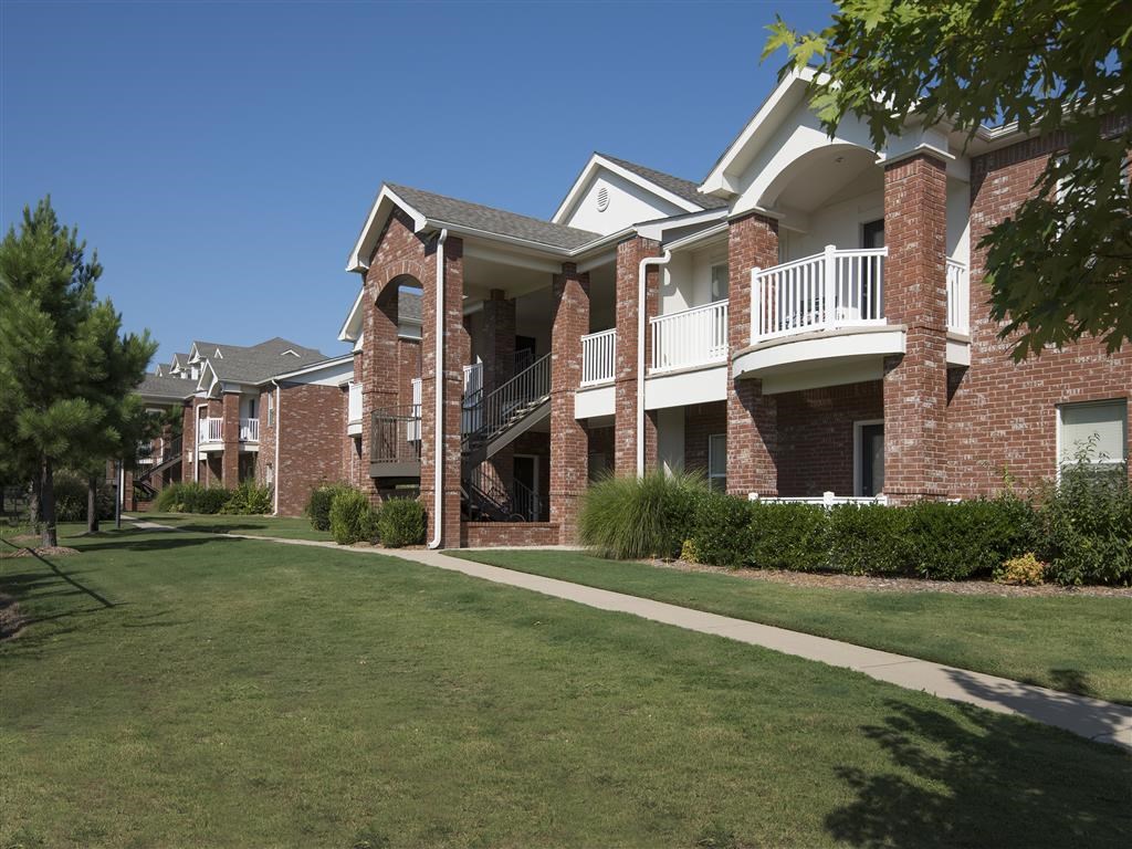 an apartment building with a green lawn and a sidewalk