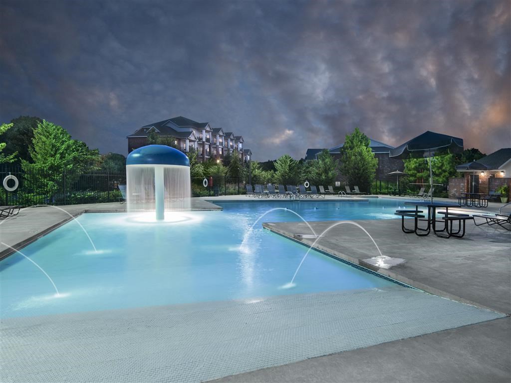 a swimming pool with a water fountain at night