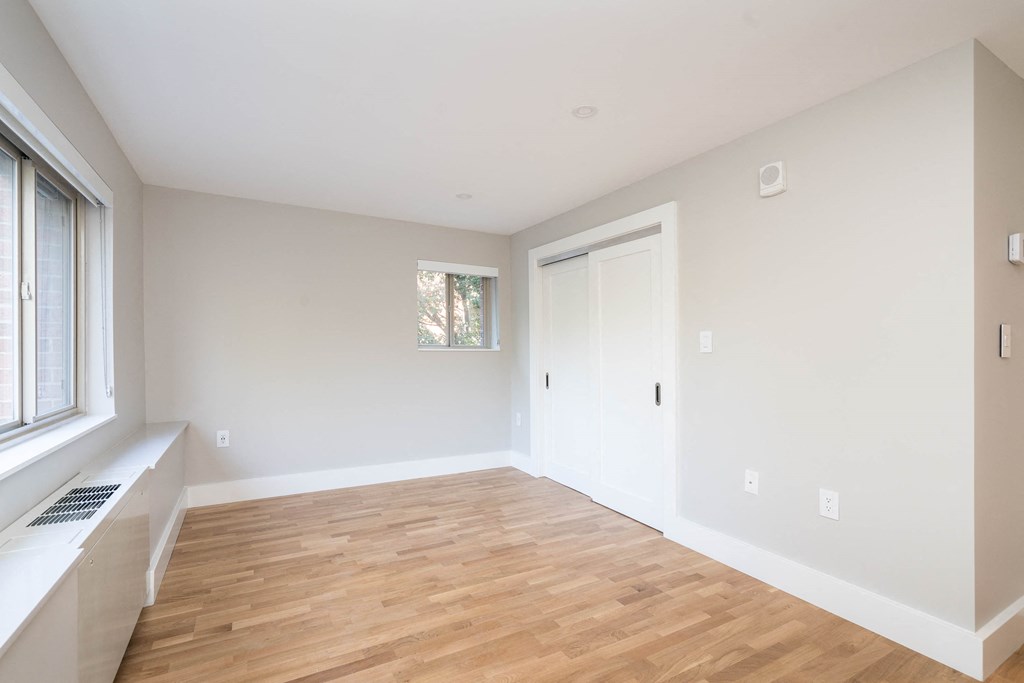 a living room with white walls and wood floors and a window