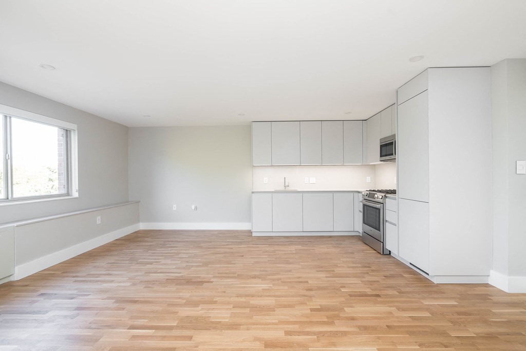 an empty kitchen with white cabinets and a wood floor