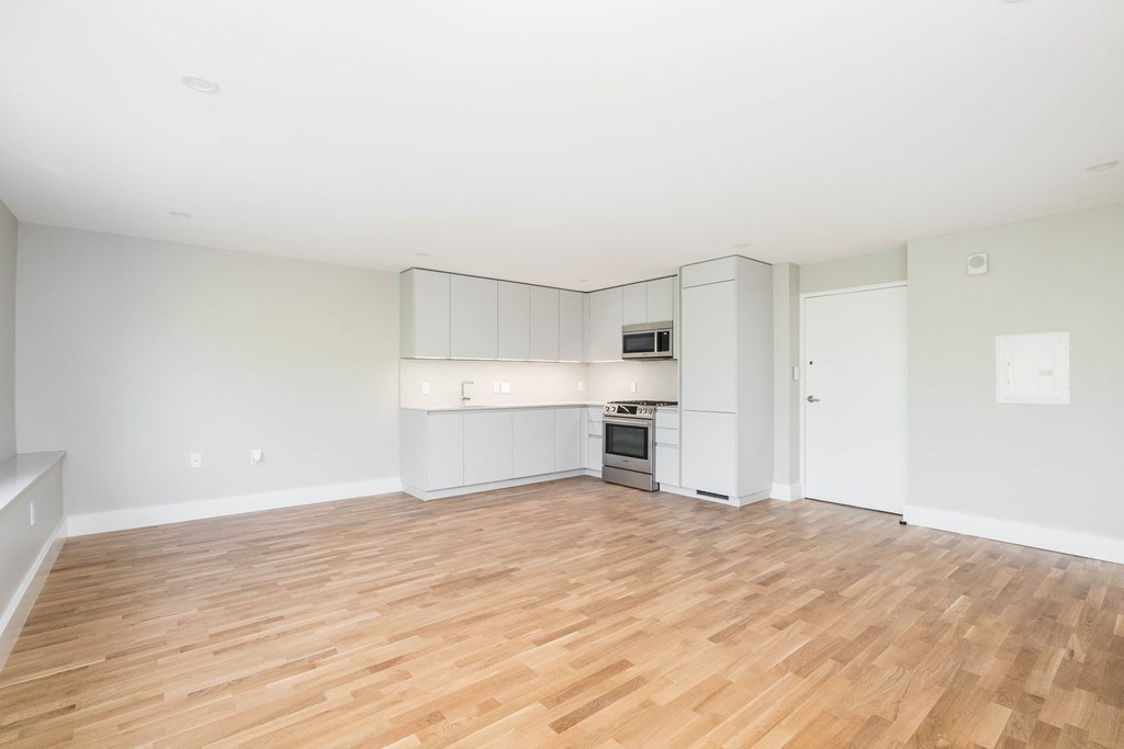 the living room and kitchen of an empty house with wood floors
