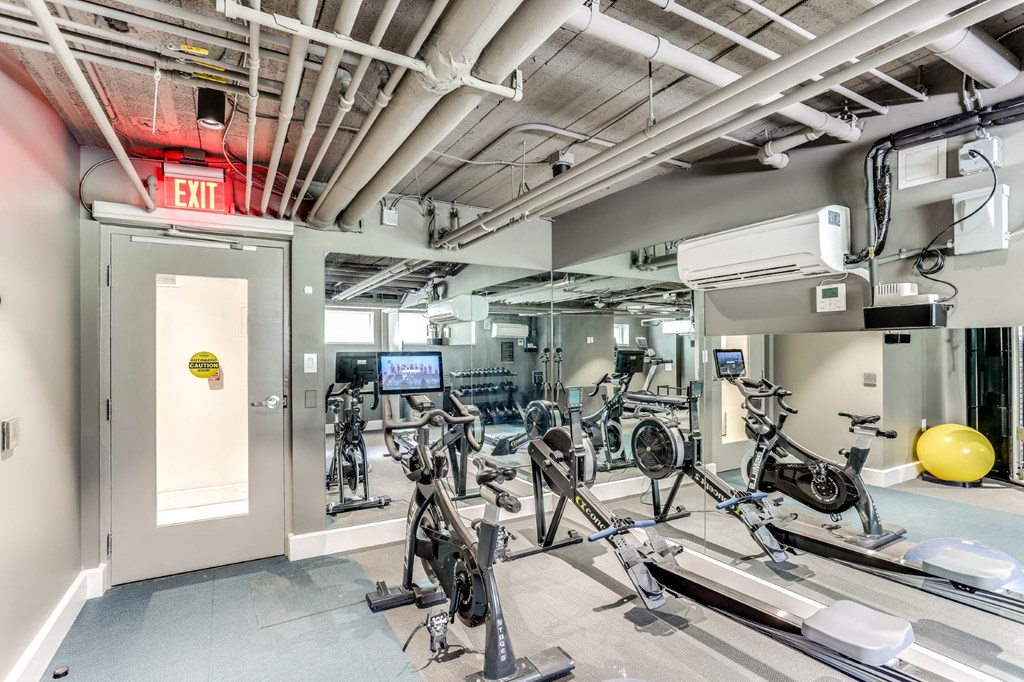 a gym with weights and bikes in a room with a door