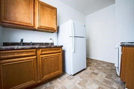a kitchen with a white refrigerator and wooden cabinets