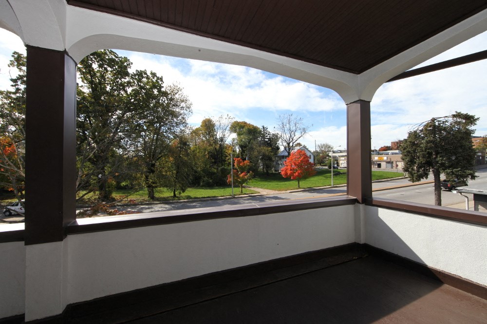 the view from the porch of the house looking out at the street and trees