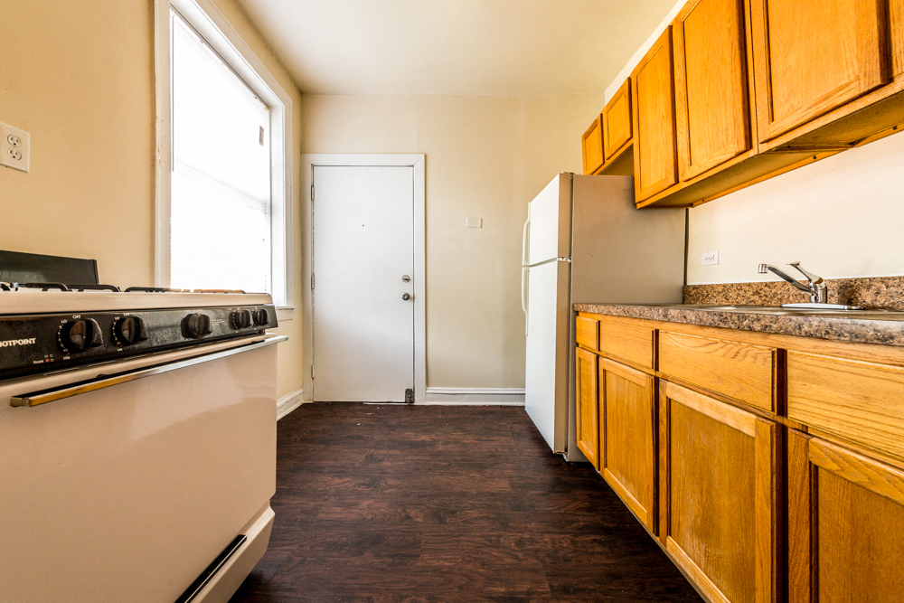 a kitchen with a stove and refrigerator and wooden cabinets
