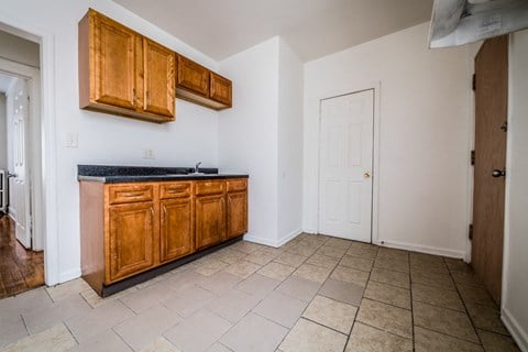 a kitchen with wooden cabinets and tiled floors and a white door