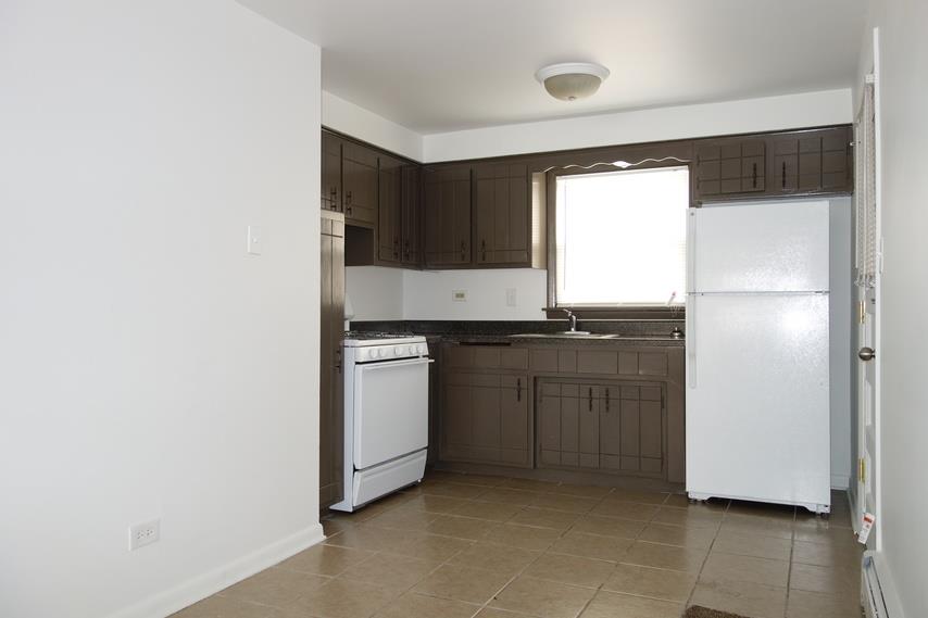 an empty kitchen with white appliances and brown cabinets