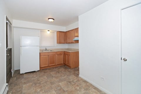 an empty kitchen with wooden cabinets and a white refrigerator