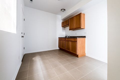 an empty kitchen with wooden cabinets and tiled floors