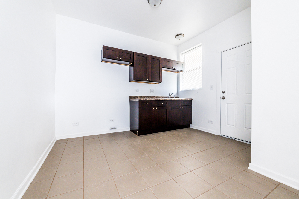 an empty kitchen with white walls and a white door