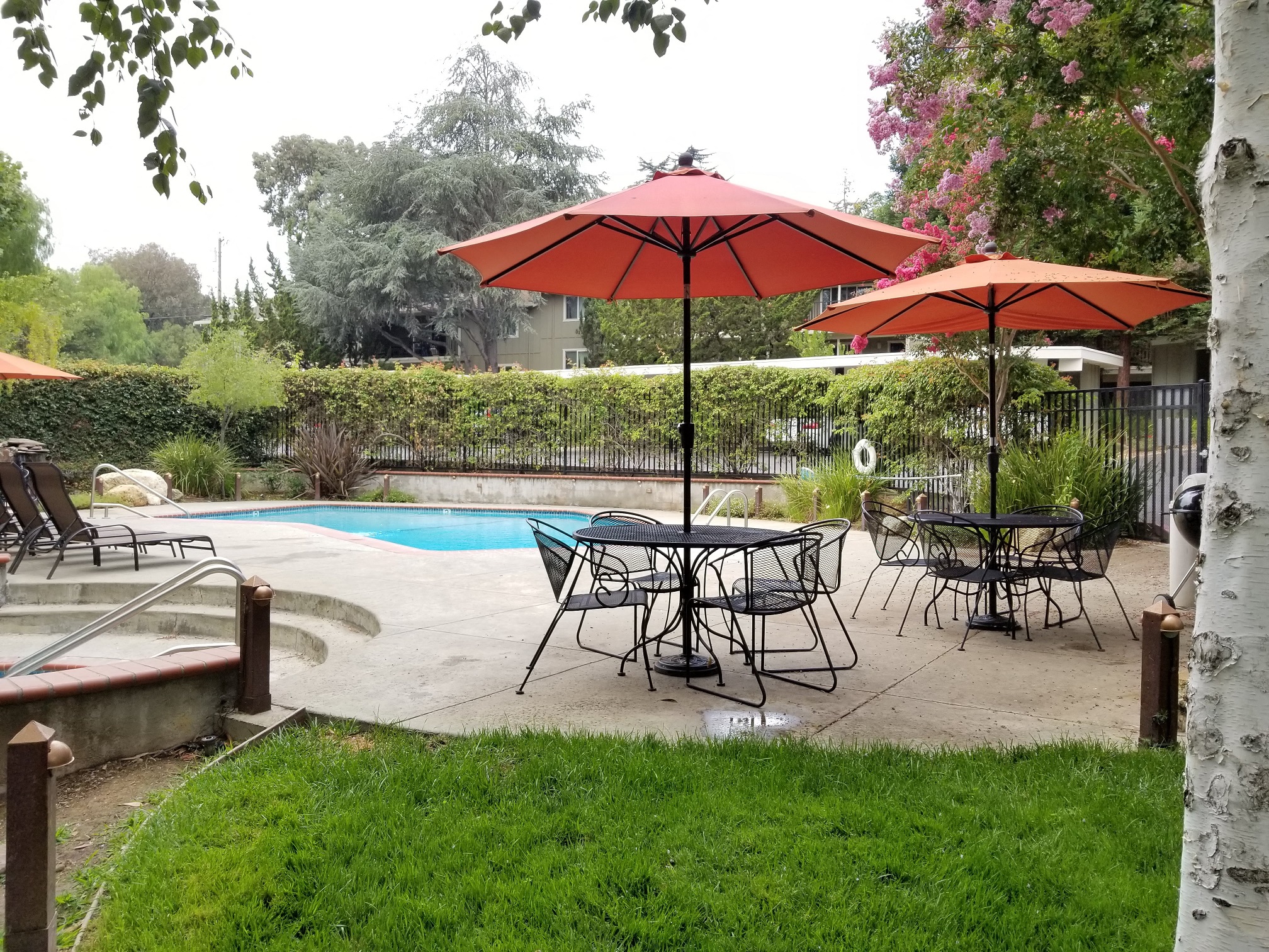 a patio with tables and umbrellas next to a swimming pool