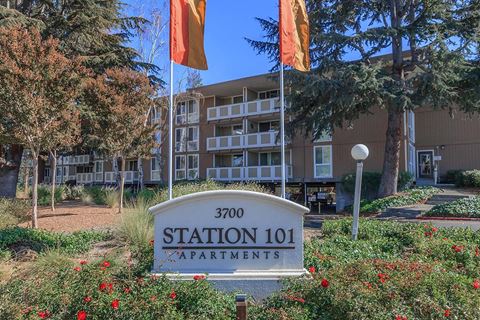 an apartment building with flags and a sign in front