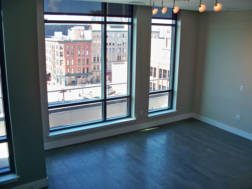 an empty living room with a wood floor and large windows