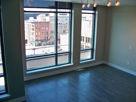 an empty living room with a wood floor and large windows