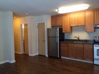 an empty kitchen with wooden cabinets and a refrigerator