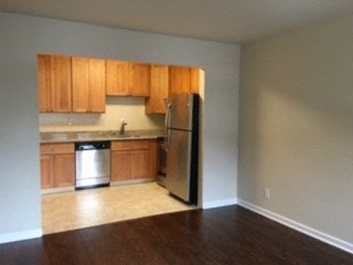 an empty kitchen with wooden cabinets and a refrigerator