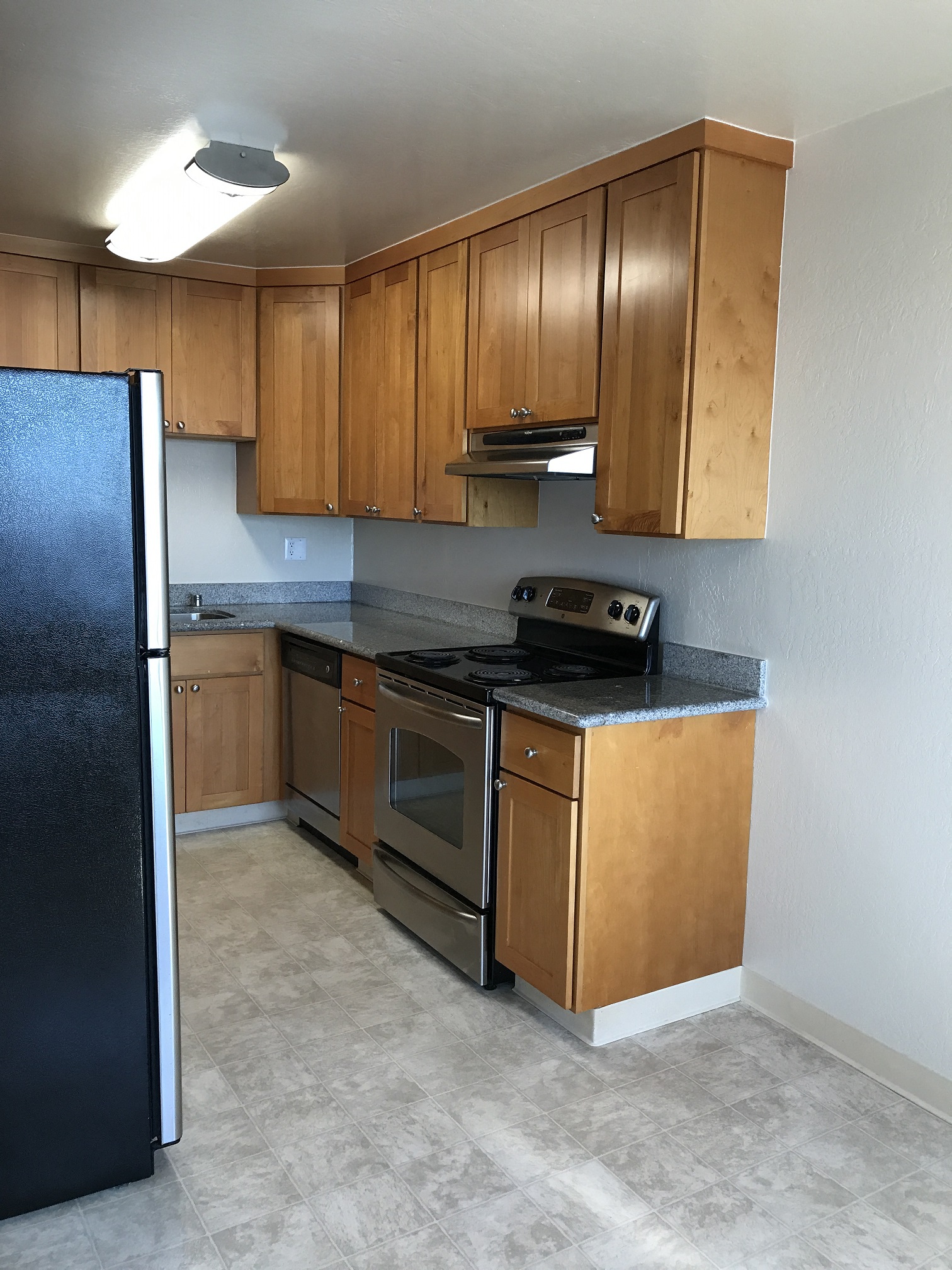 an empty kitchen with wooden cabinets and stainless steel appliances