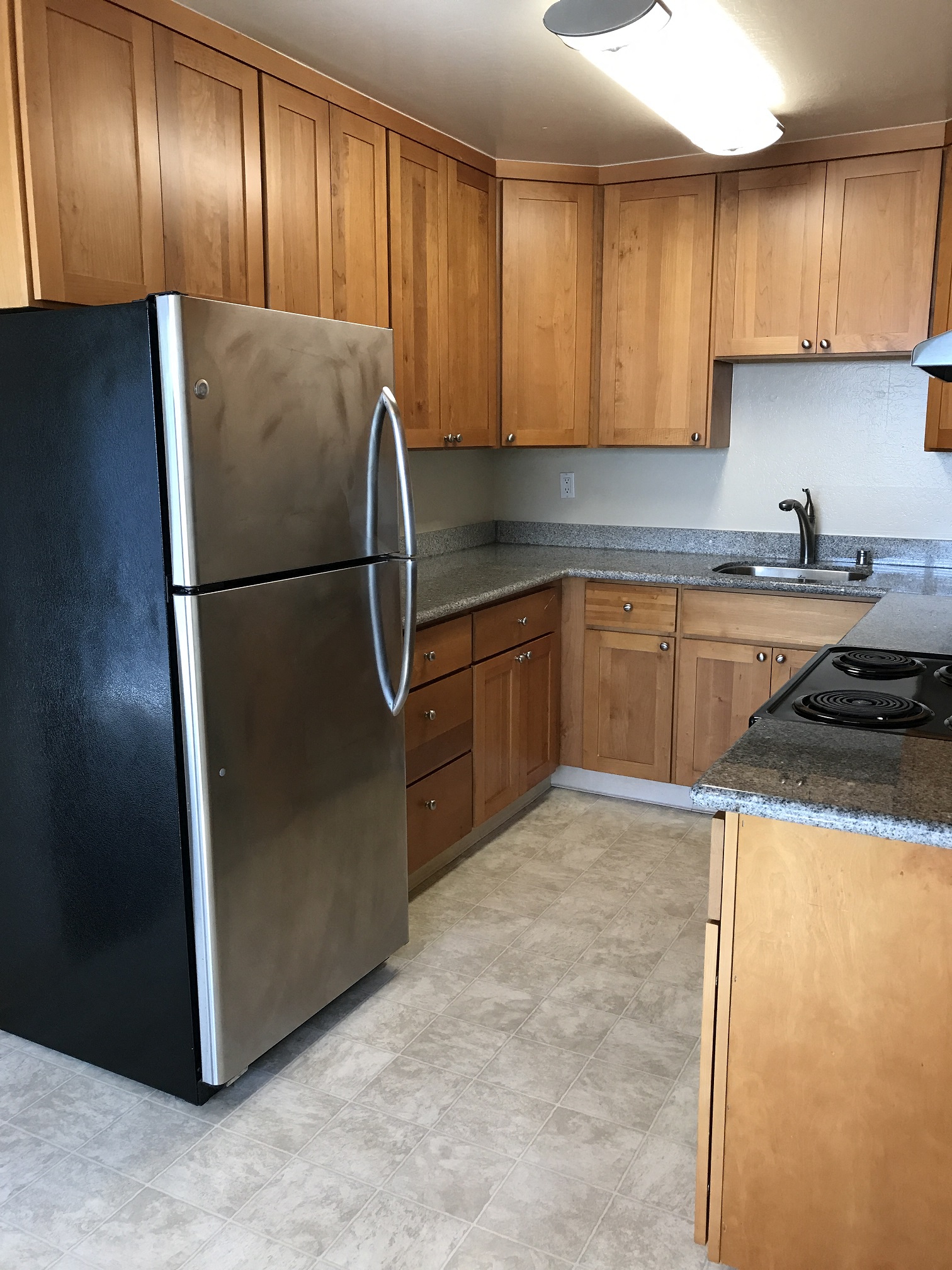 a kitchen with wooden cabinets and a stainless steel refrigerator