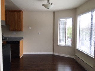 an empty room with a kitchen and a large window