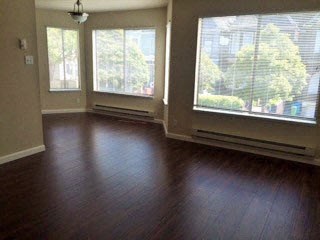 an empty living room with wood floors and large windows