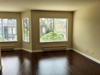 an empty living room with wood floors and large windows