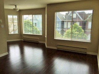 an empty living room with wood floors and large windows