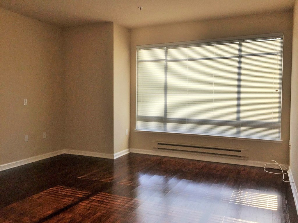 an empty living room with a large window and wooden floors