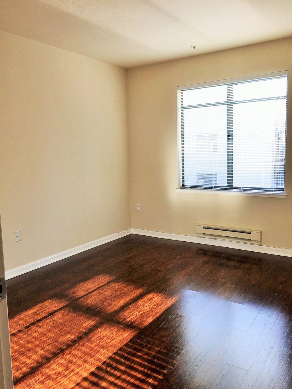 an empty living room with wood floors and a window