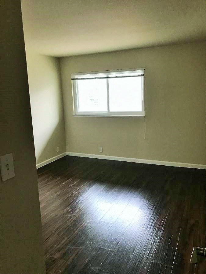 an empty room with wooden floors and a window