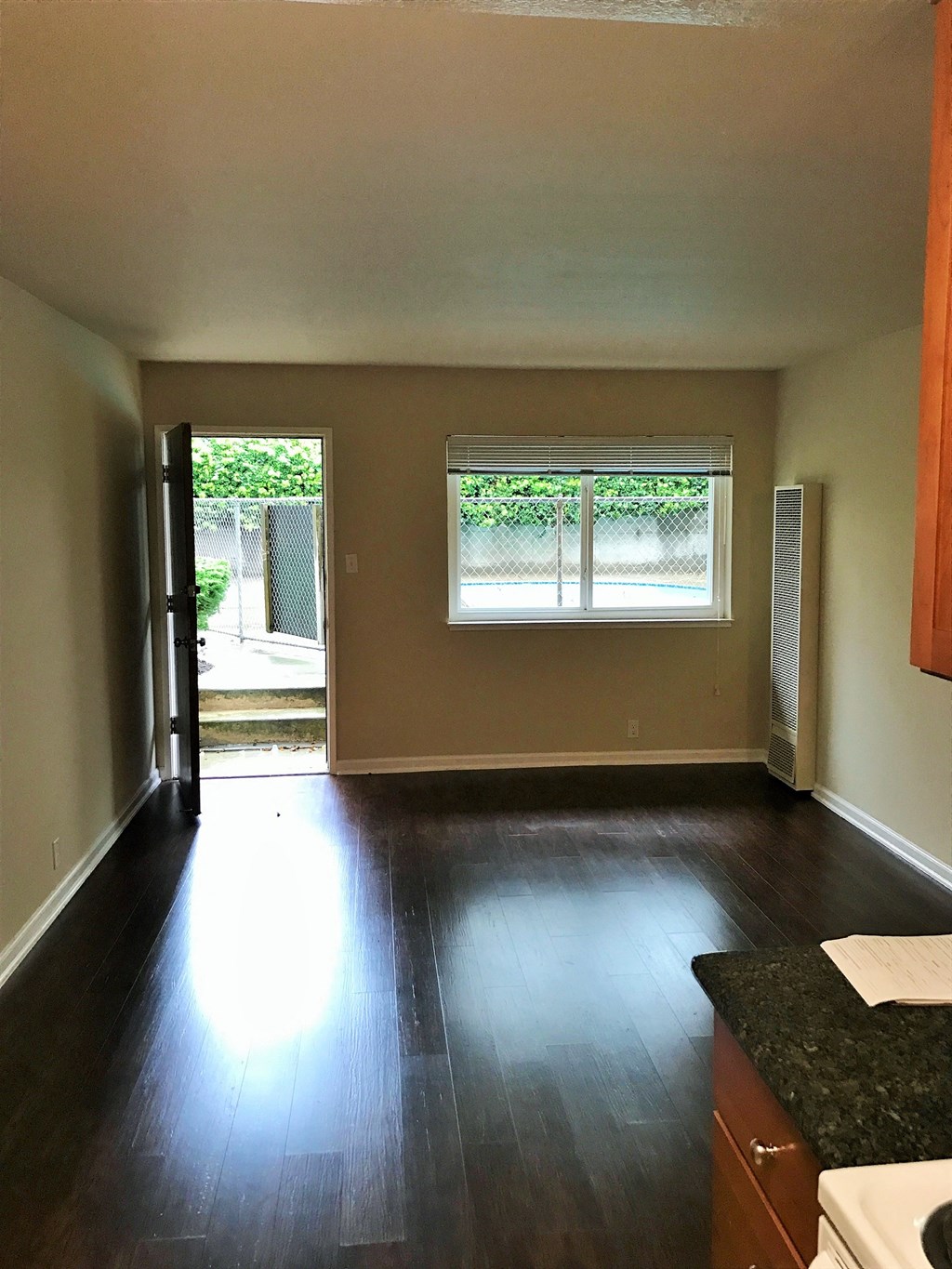 an empty living room with hard wood floors and a window