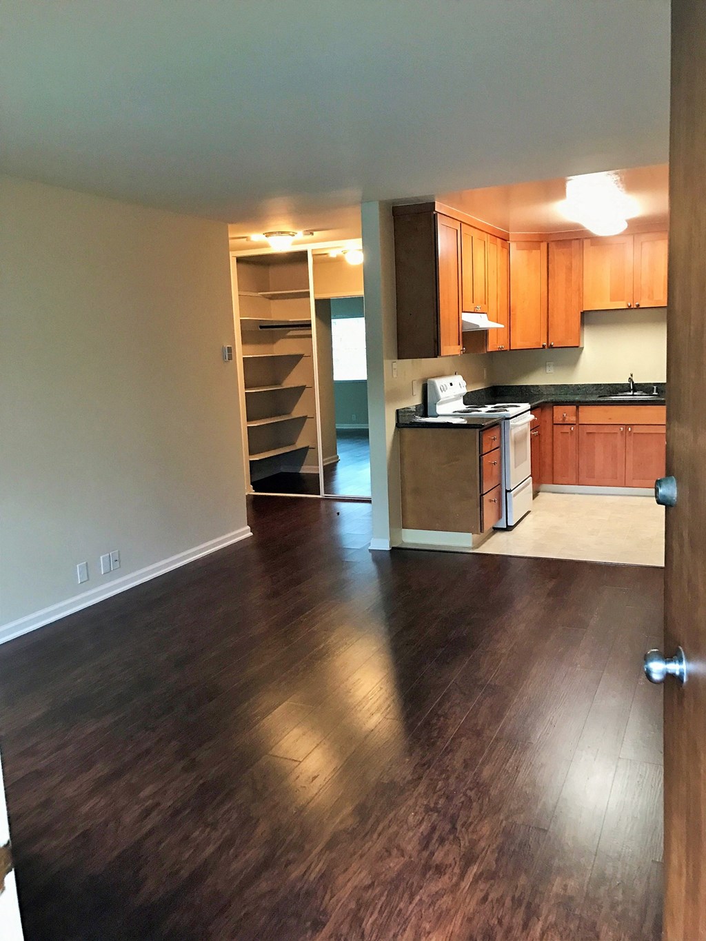 an empty living room and kitchen with wood flooring