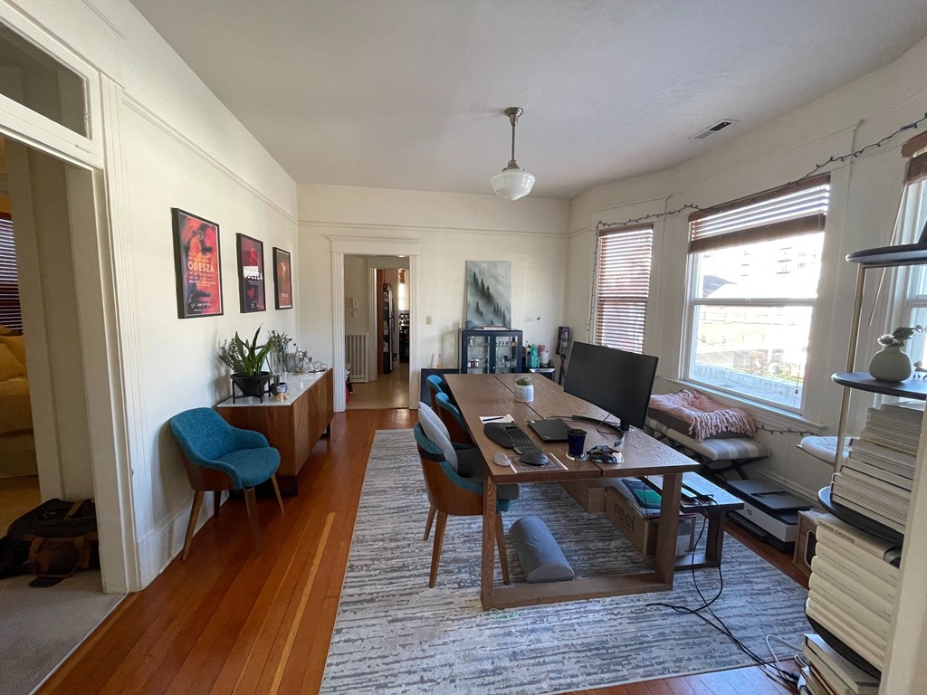 a dining room and living room with a desk and a tv
