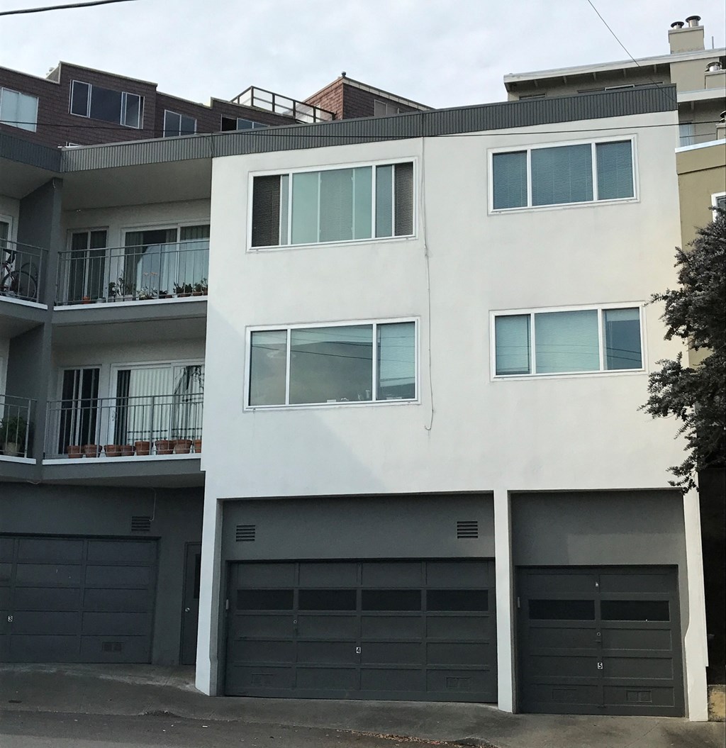 a white apartment building with garage doors