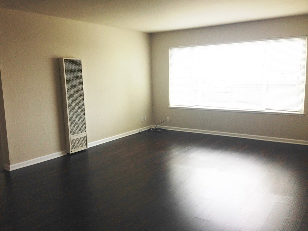 an empty living room with wood floors and a window
