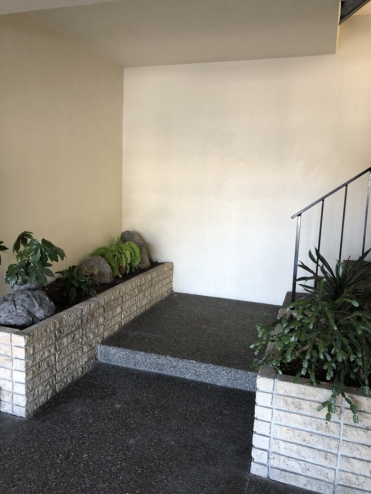 a stone planter with plants on the side of a building