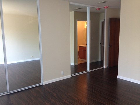 an empty living room with wood floors and mirrors