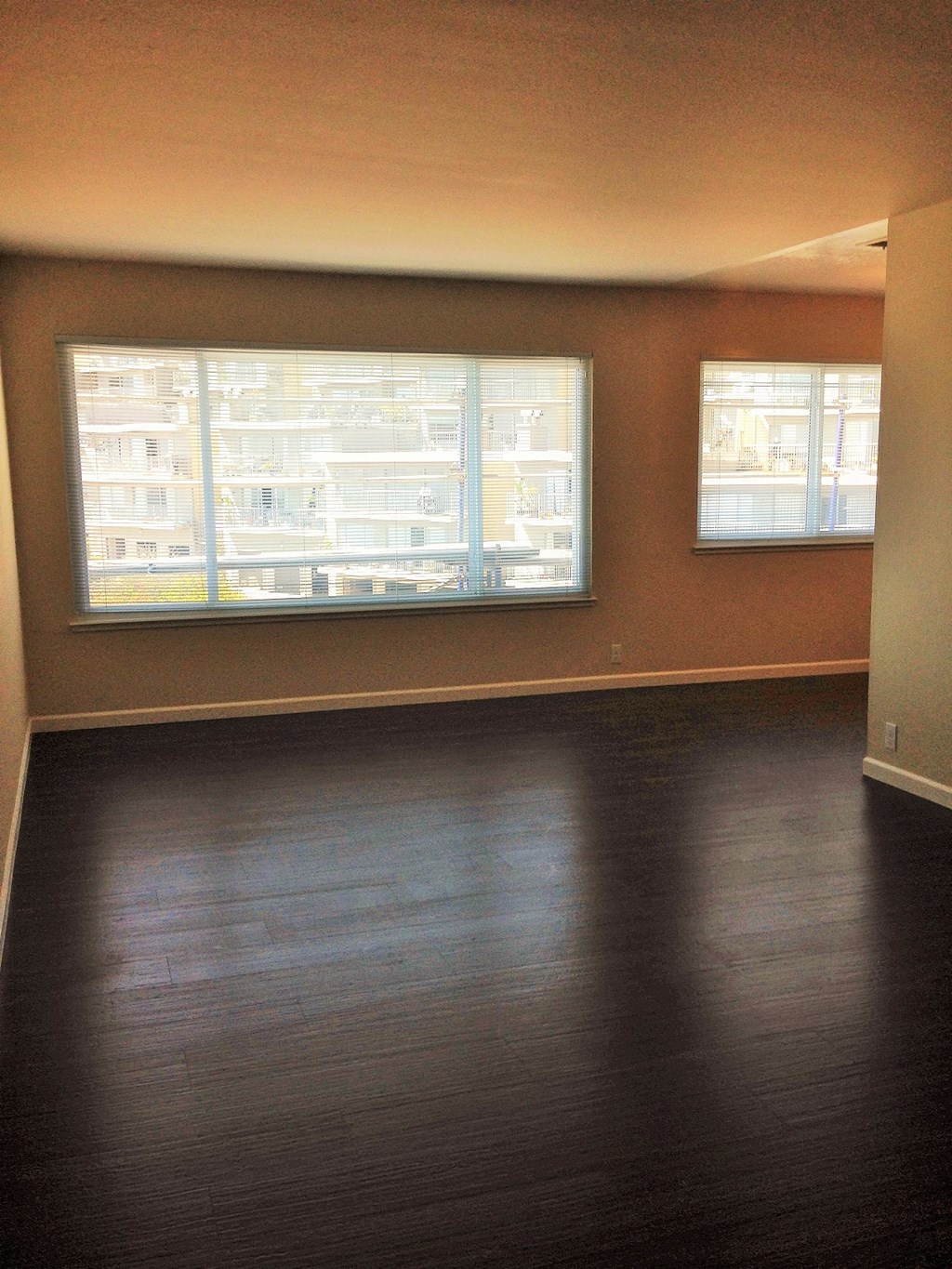 an empty living room with wood floors and large windows