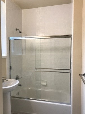a white bathroom with a shower and a sink