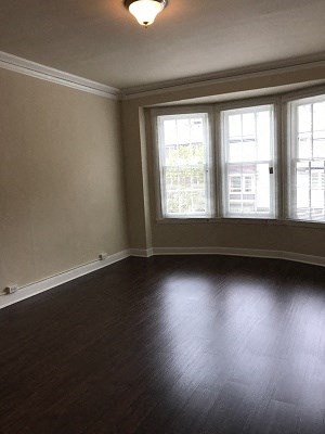 an empty living room with a wood floor and three windows