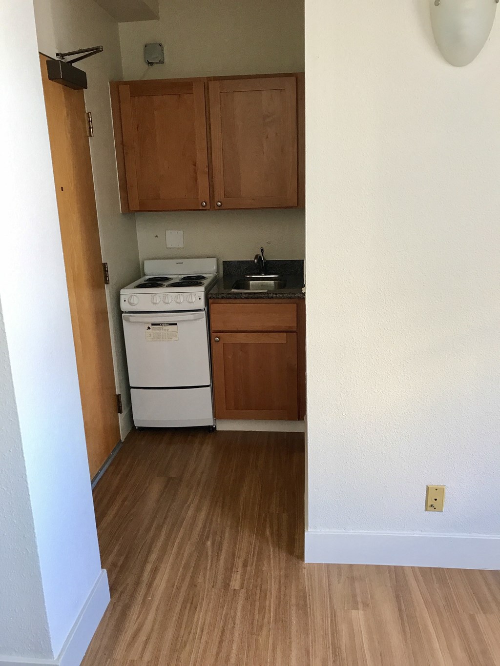 an empty kitchen with wooden flooring and a white stove and refrigerator